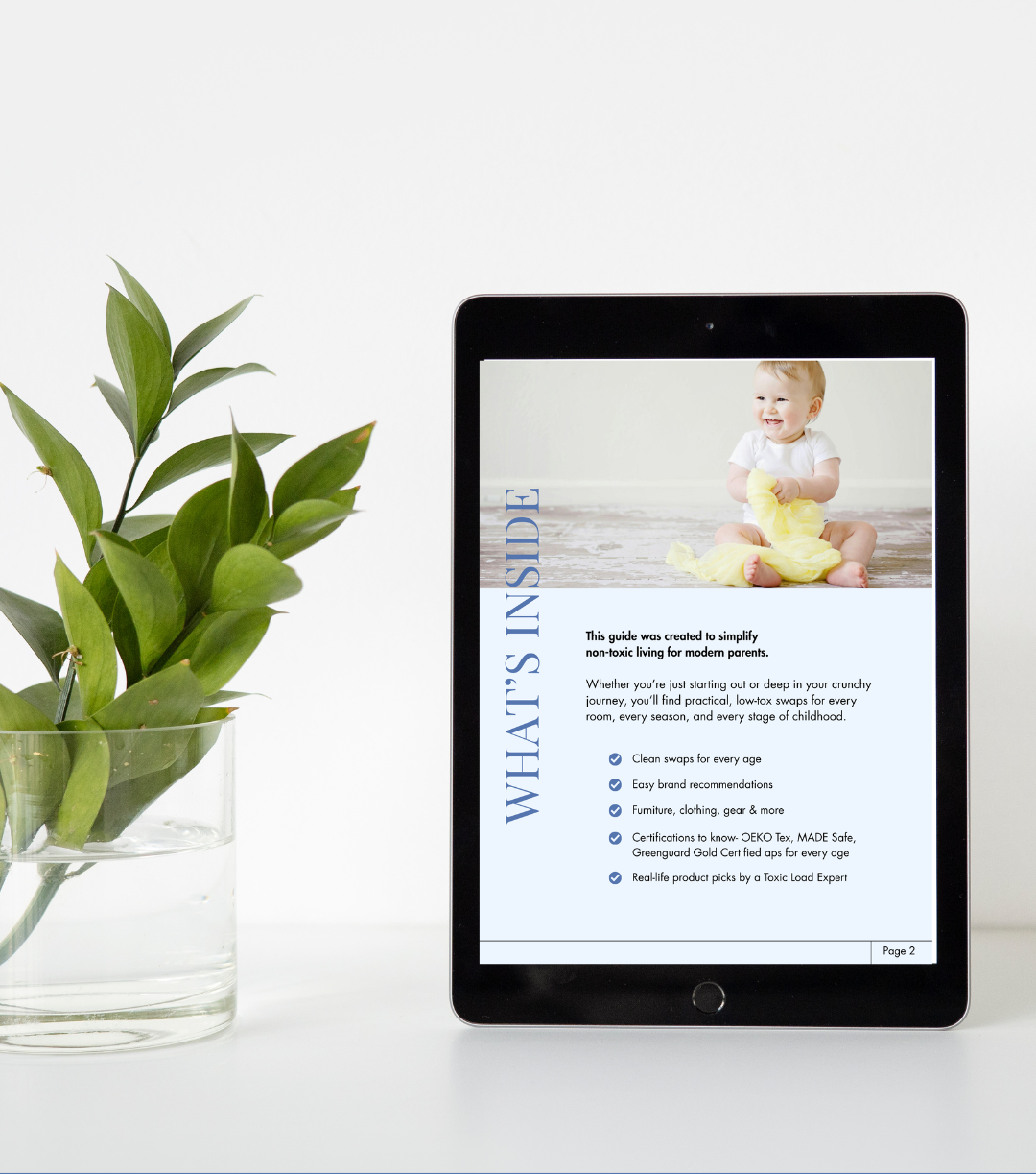 Tablet displaying a baby product guide on a white surface with a plant.