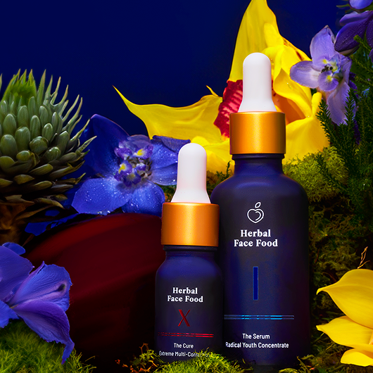 Two bottles of 'Herbal Face Food' with droppers surrounded by flowers on a dark background