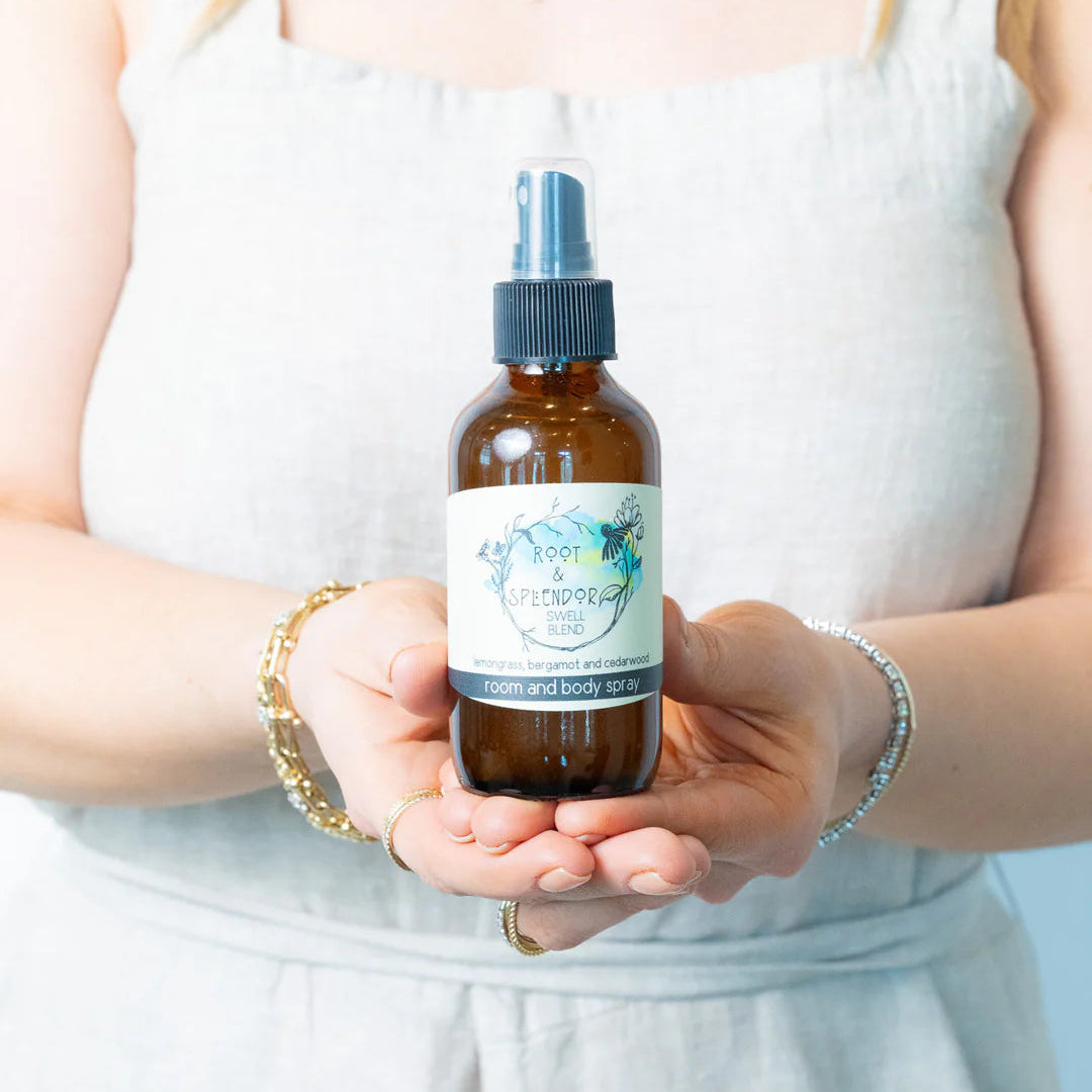 Person holding a brown spray bottle with a label against a white background