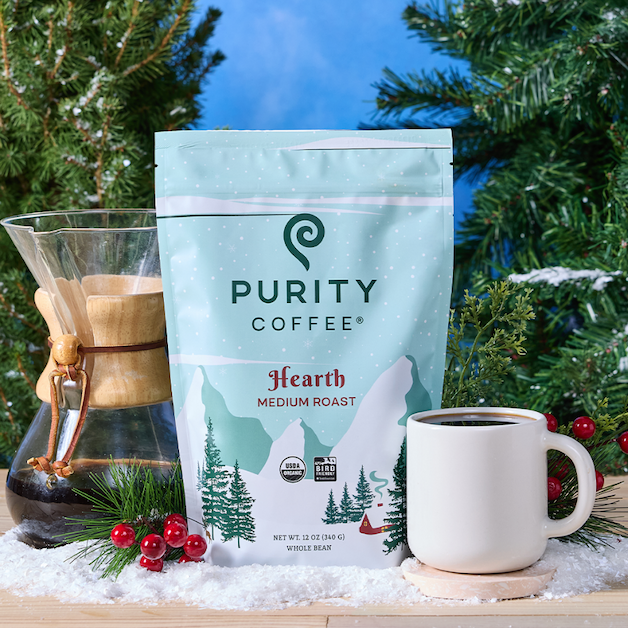 Purity Coffee Hearth Medium Roast package with a mug and coffee maker against a Christmas-themed background.
